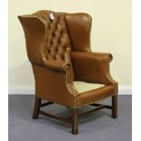 A 20th Century George III style wing back armchair, upholstered in buttoned brown leather, on