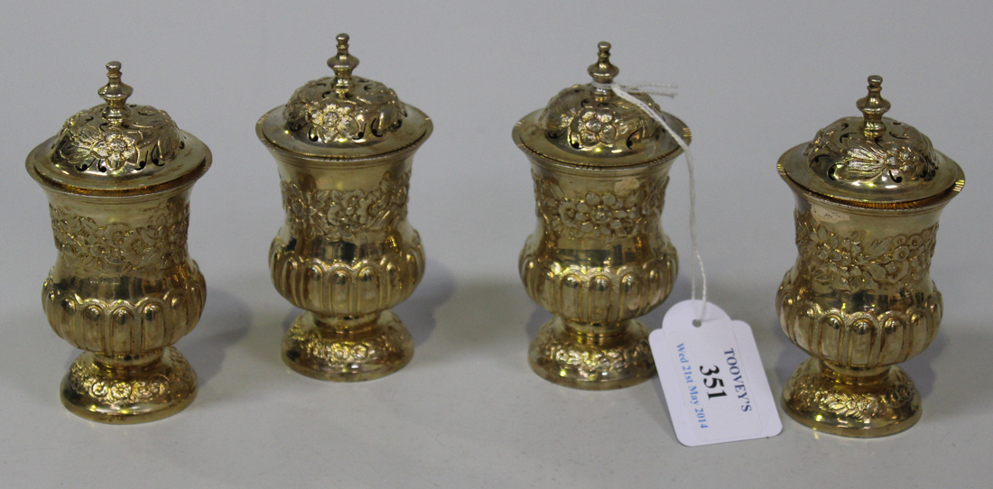 A set of four George V silver gilt sanders, each with pierced domed cover and knop finial above an