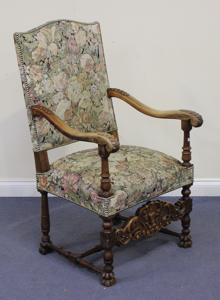 An early 20th Century Continental walnut open armchair, upholstered in machined floral tapestry, the