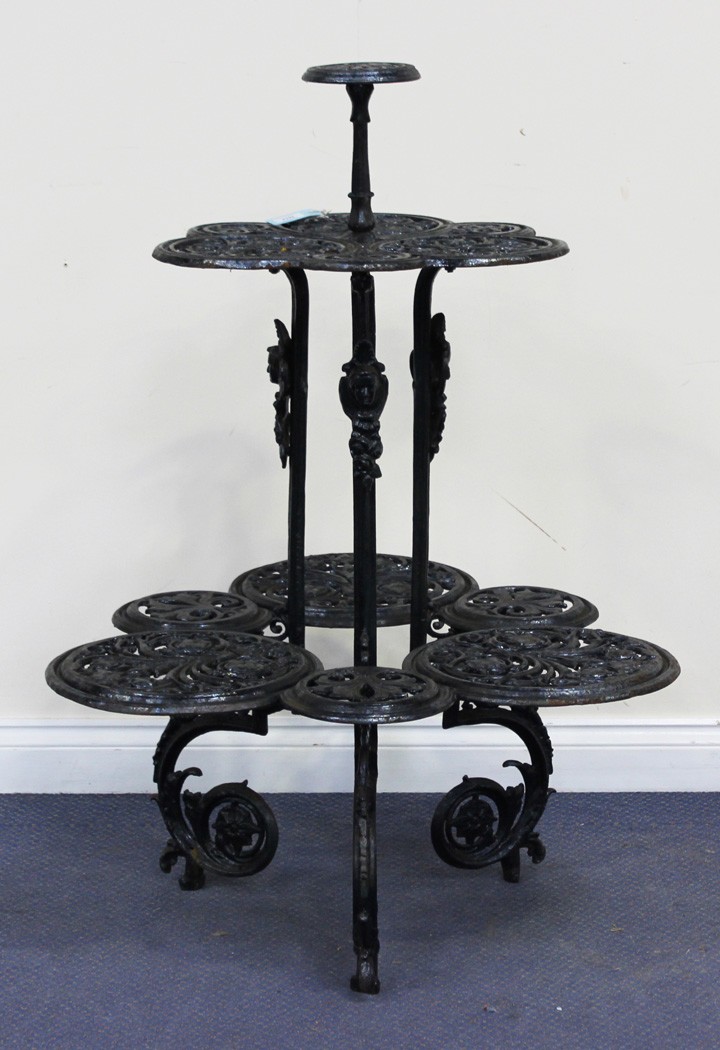 A Victorian style black painted cast iron plant stand with three graduated tiers of pierced