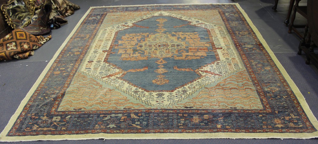 A Turkish carpet, mid-20th Century, the faded blue field with a shaped foliate medallion, within