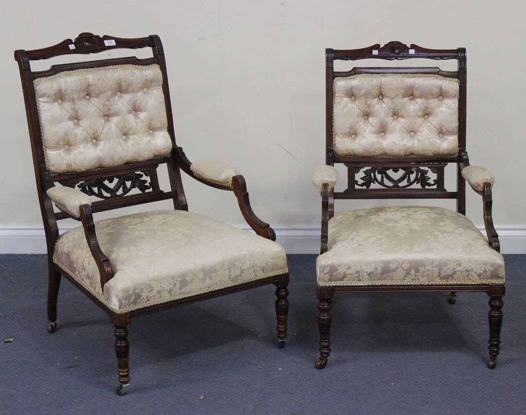 A pair of Edwardian walnut showframe open armchairs upholstered in foliate patterned damask, the