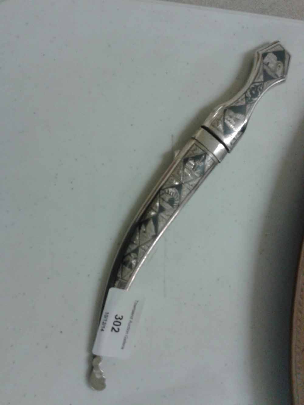 A small white metal dagger with Far Eastern engraved decoration.