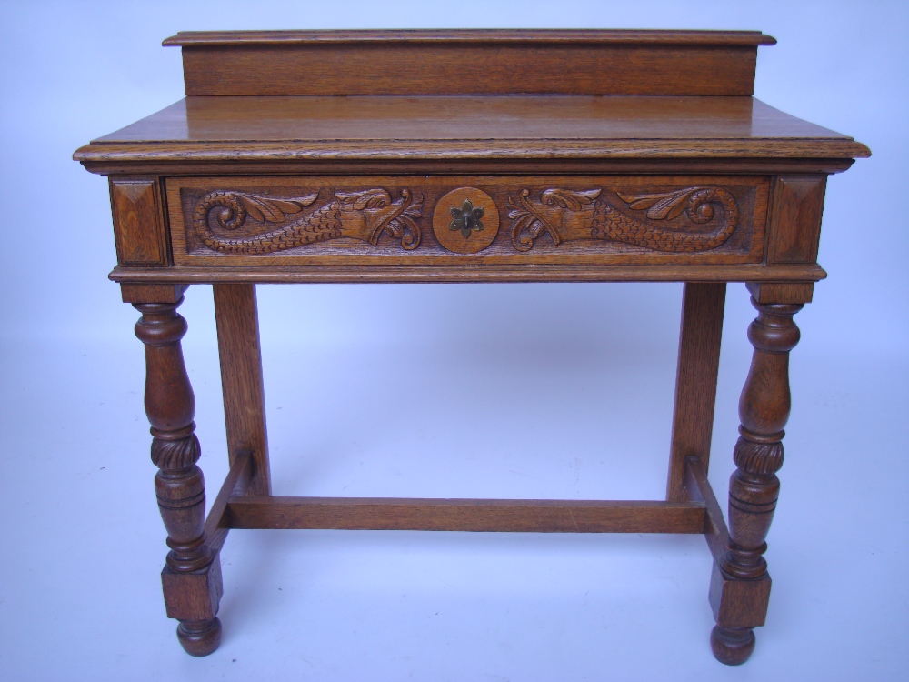 A late Victorian oak side table, the frieze drawer carved with mythical dolphins, on turned front