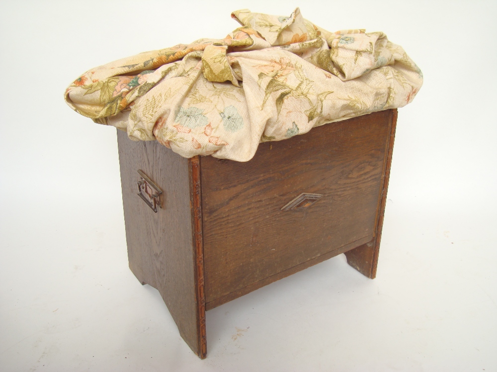 A 1920's oak dressing table stool with copper handles, upholstered with hinged compartment.