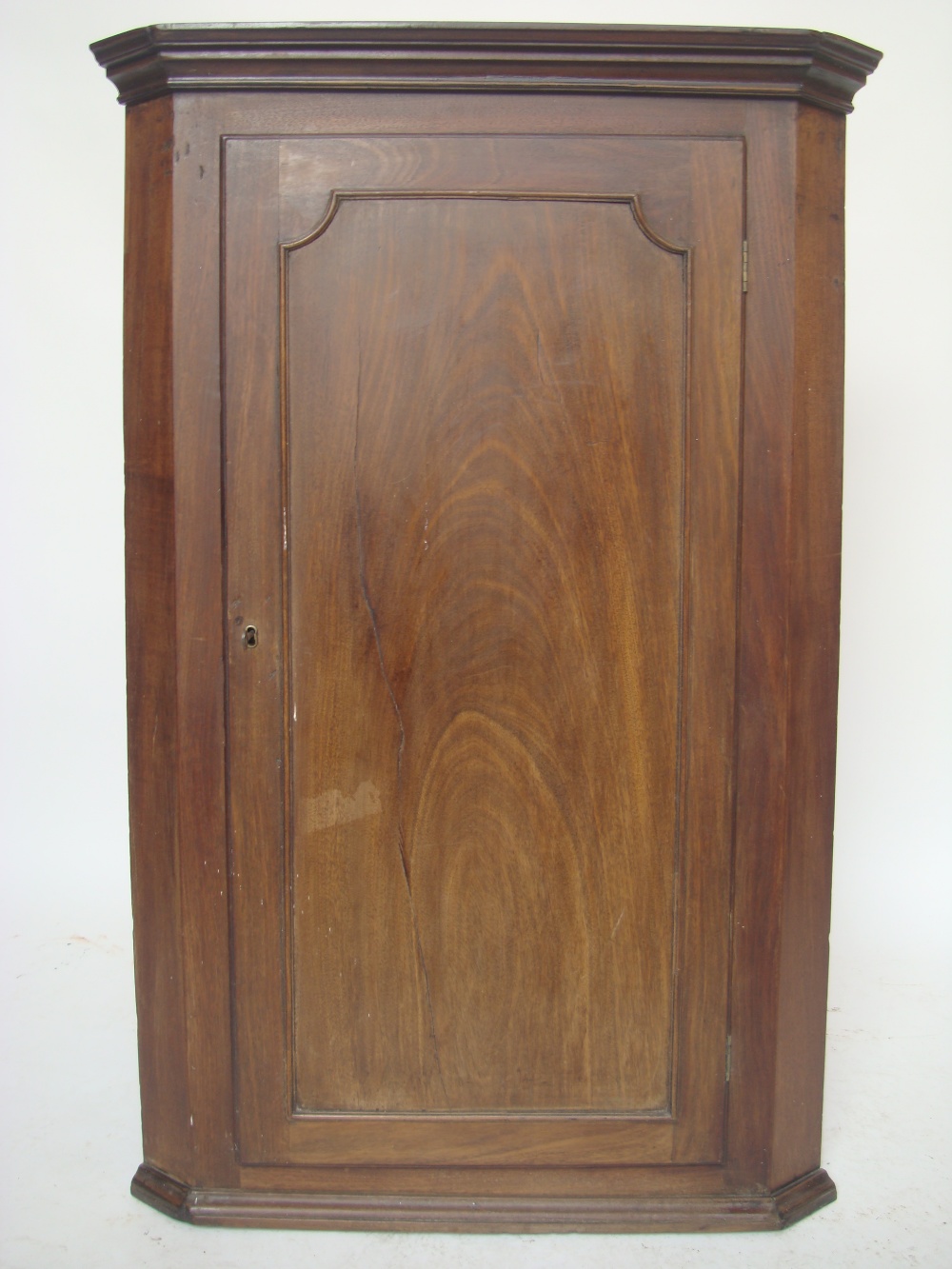 A George III mahogany hanging corner cupboard.
With moulded projecting cornice, the panelled