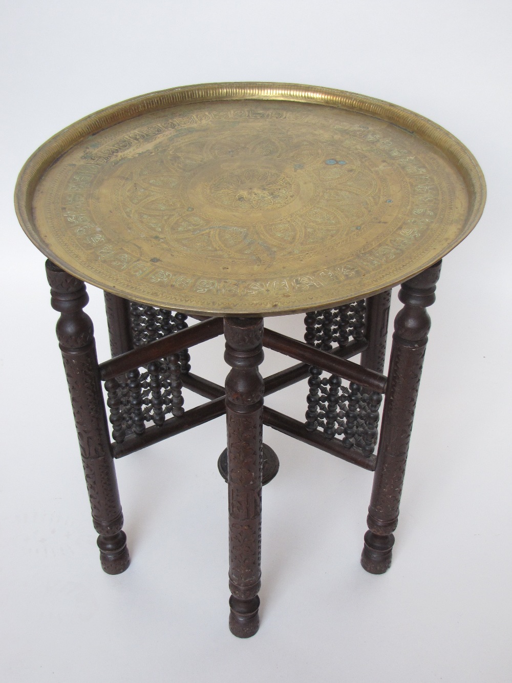 An Indian brass topped tea table on folding stand.