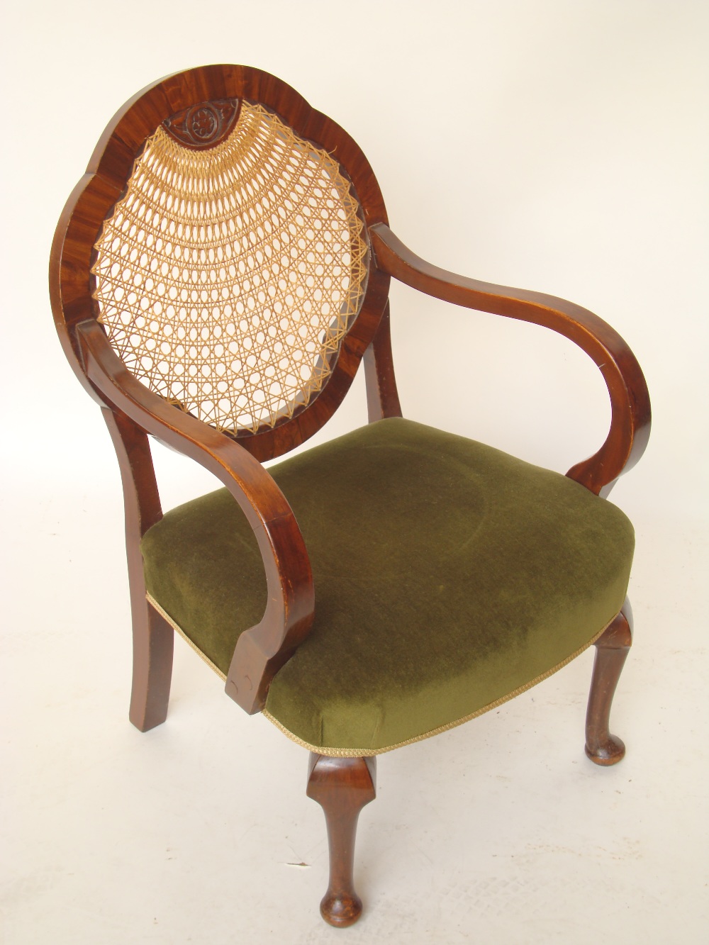 A 1930's open elbow chair with caned black and green velvet stuff over seat.