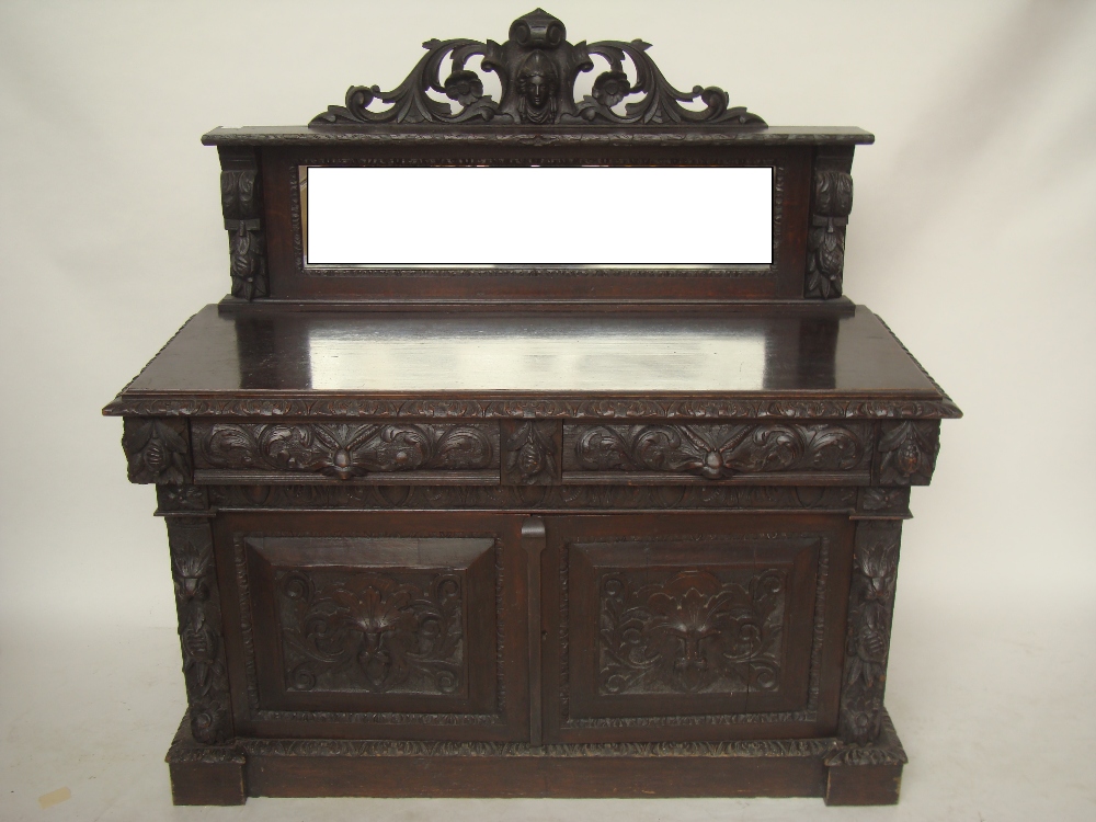 A late Victorian carved oak buffet, the mirror back with pierced carved crest piece over base with