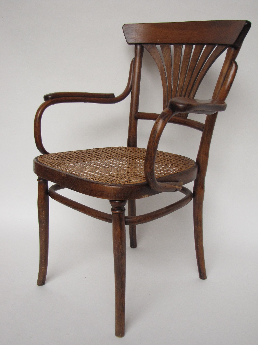 An early 20th Century Thonet bentwood open elbow chair with caned seat, stamped Thonet.
