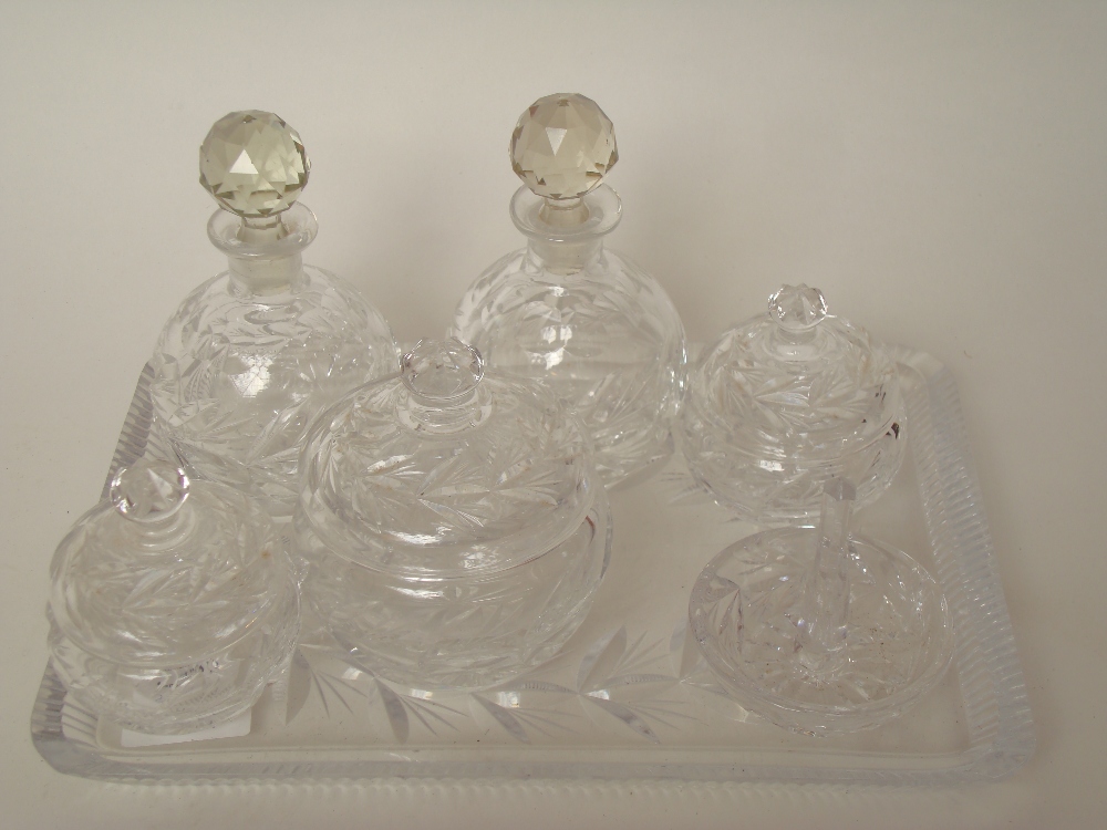 A cut glass seven piece dressing table set comprising, a pair of scent bottles and stoppers, a