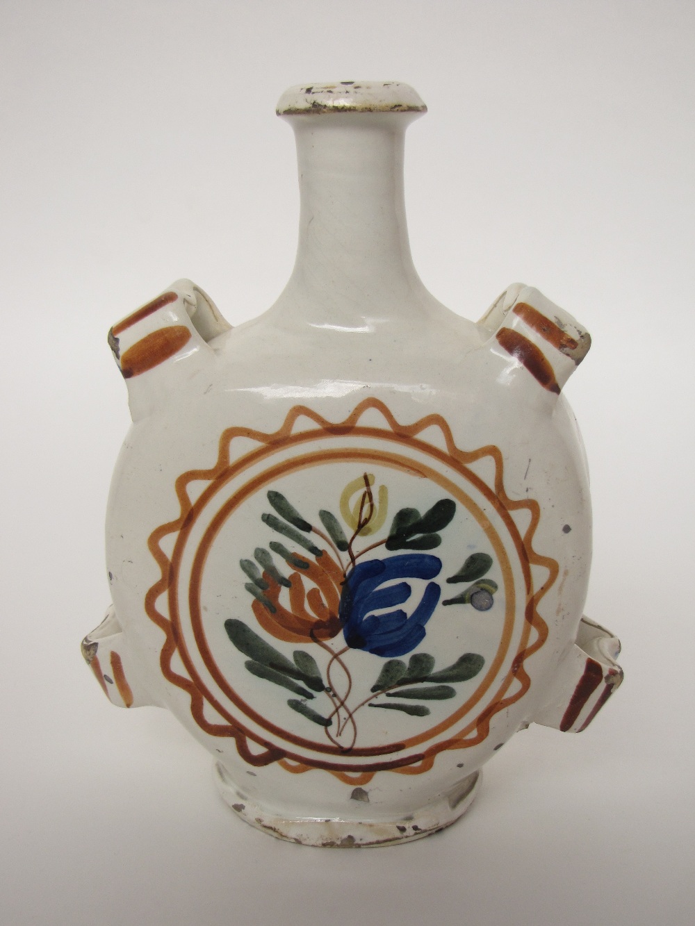 A 19th century continental faience flask with applied straps, the body loosely painted in polychrome