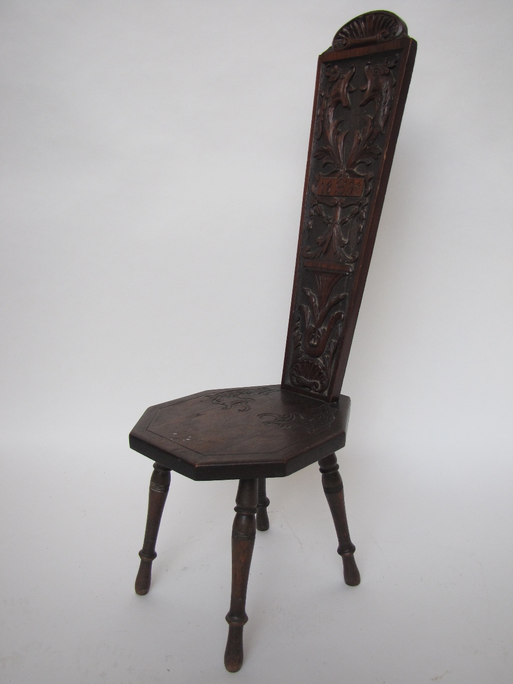 A late 19th Century walnut spinning chair, the splayed back and seat carved with mythical dolphins