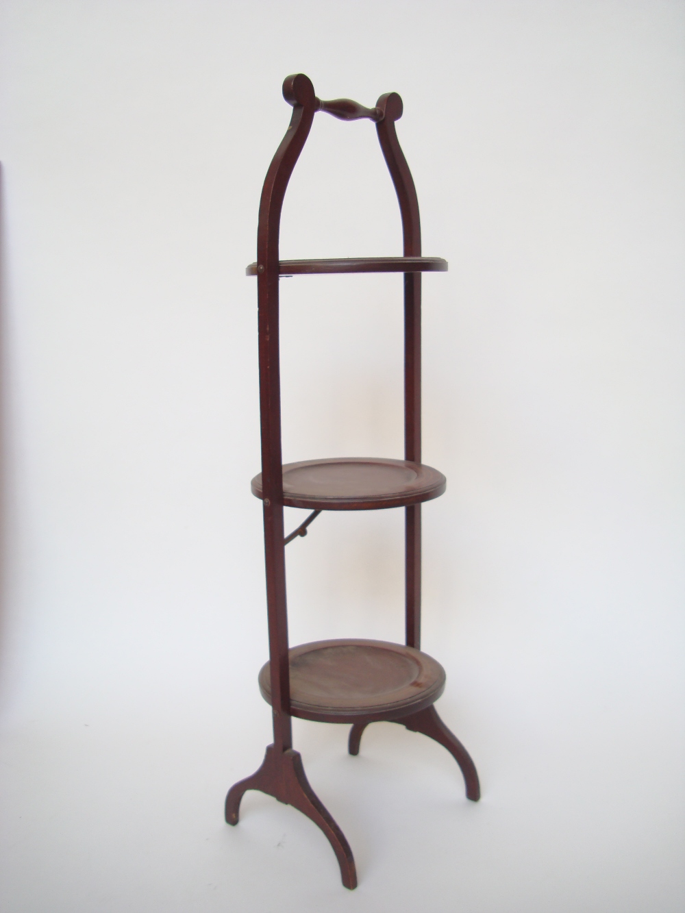 An Edwardian mahogany three tiered mahogany folding cake stand.