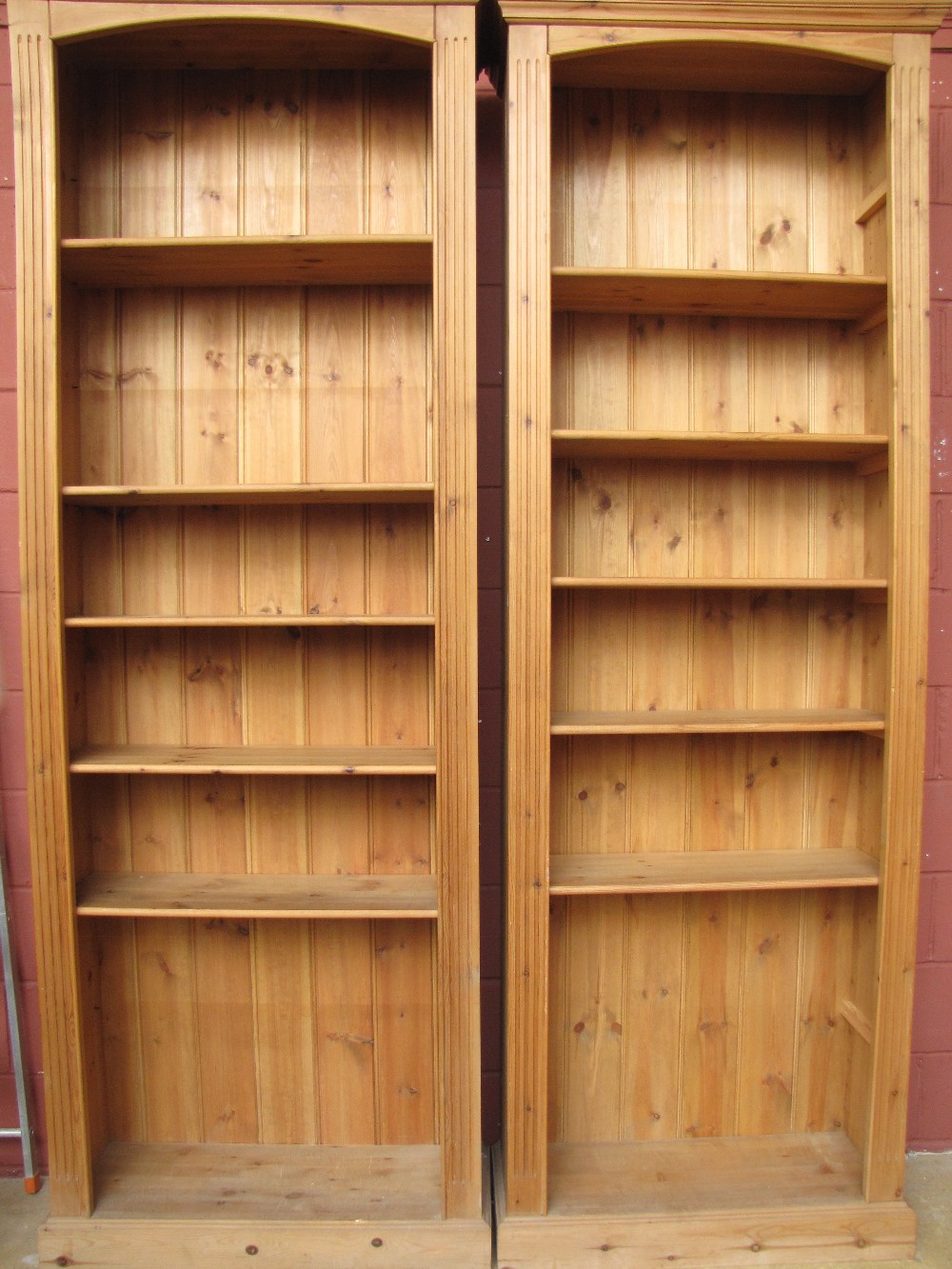 A pair of tall pine open bookcases with adjustable shelves.