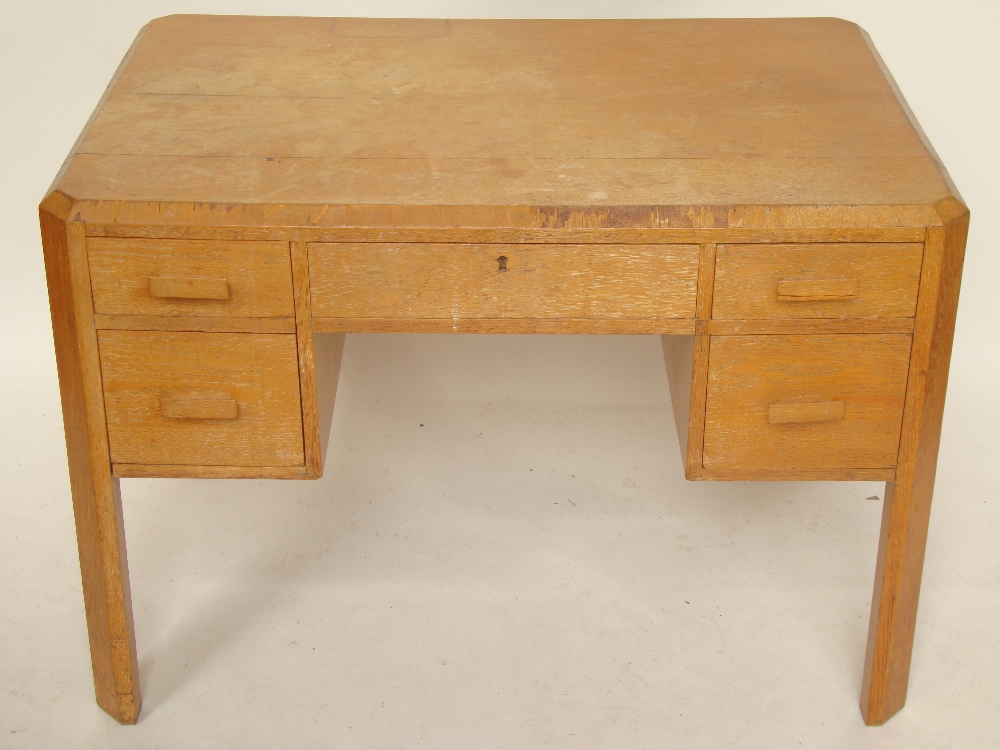 A 1930's Heals style light oak partners desk, the rectangular top with canted corners and sides,