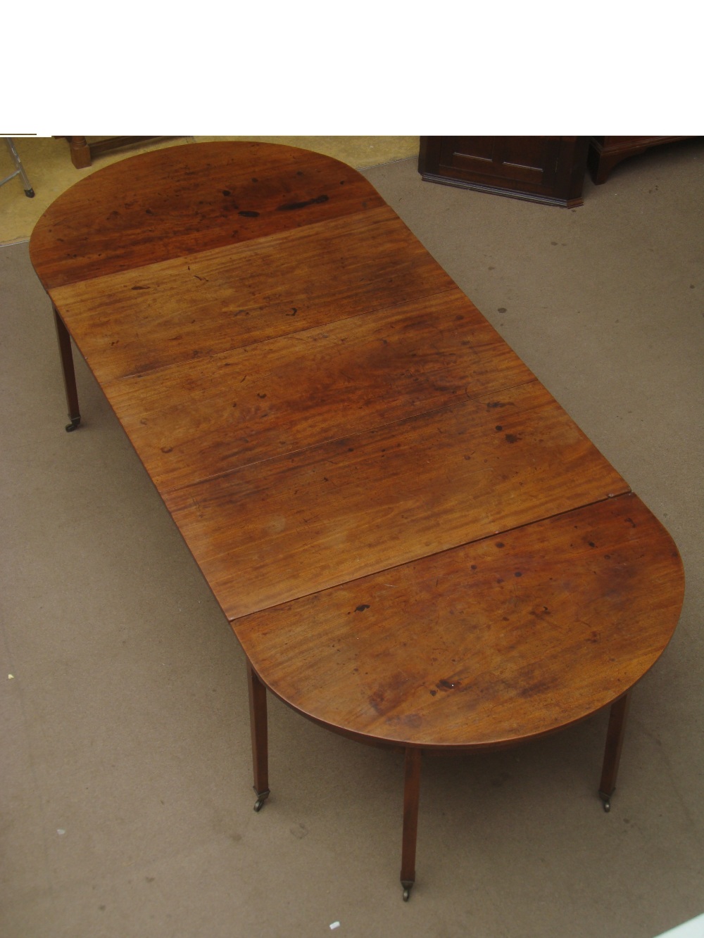 A George III mahogany D end dining table, the central rectangular section with two hinged leaves and