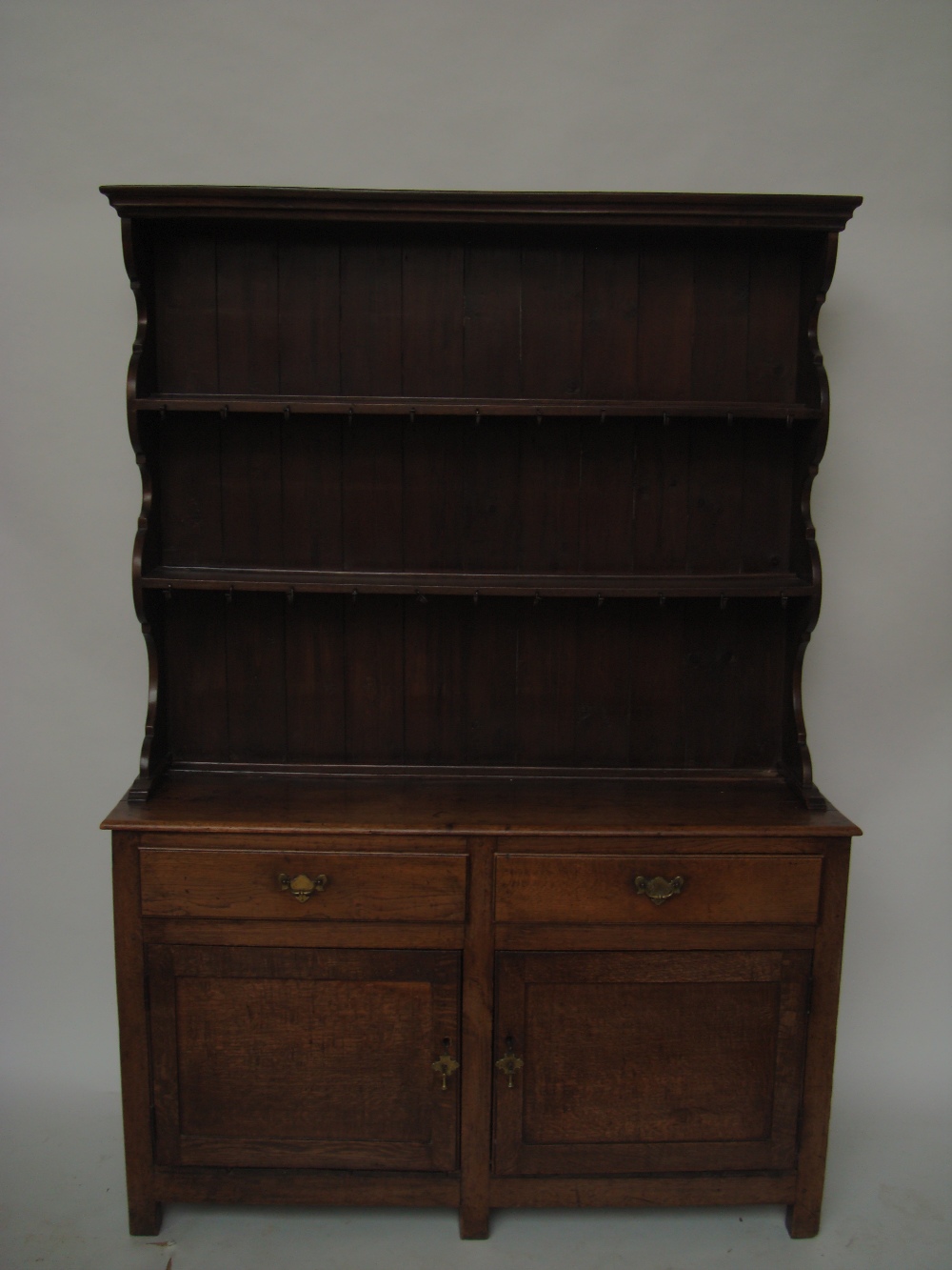 An 18th Century and later oak dresser, the later upper section with moulded cornice above two