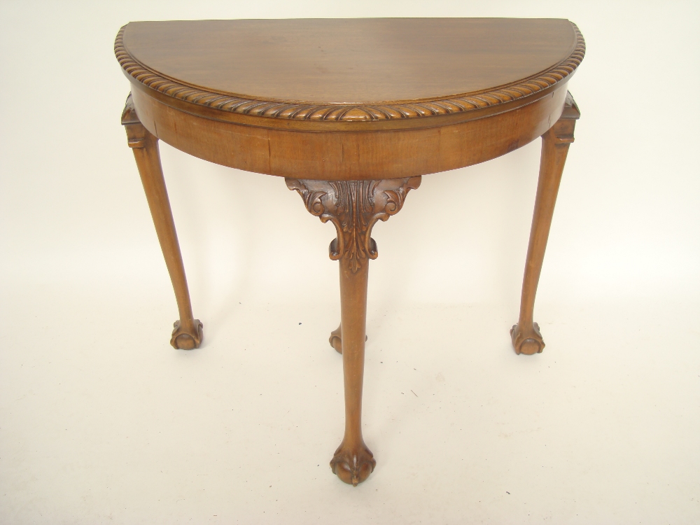 An early 20th Century mahogany demi lune fold over card table, the top with gadrooned edge opening