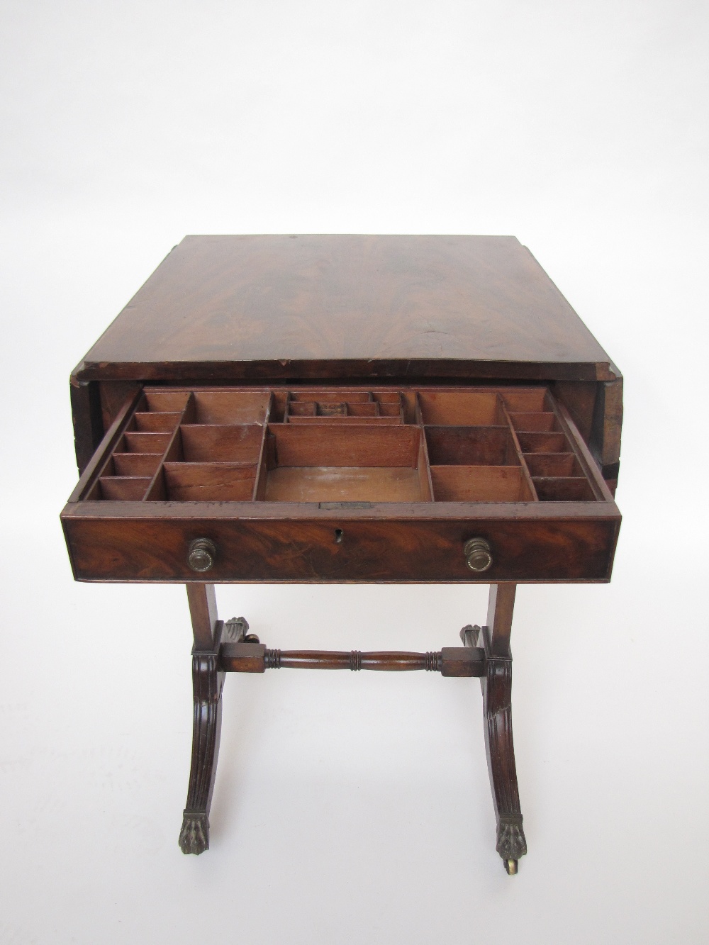 A Regency mahogany work table, the figured mahogany top with twin hinged flaps over a frieze
