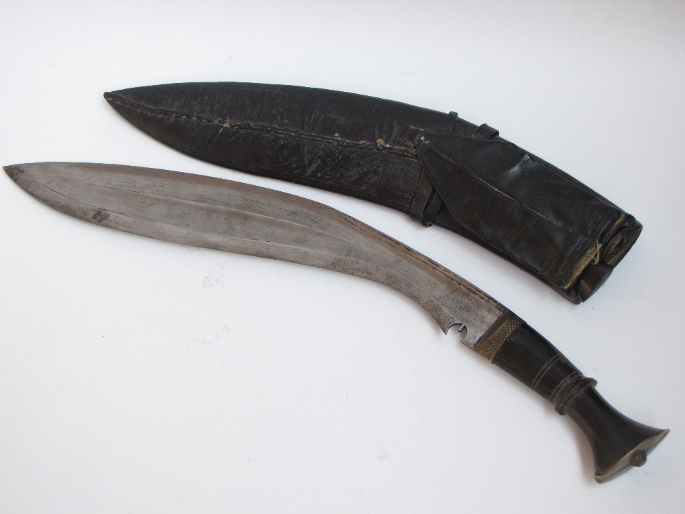 A Nepalese Kukri with horn grip in leather sheath with twin smaller blades.