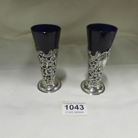 A pair of silver posy holders with blue glass liners, a/f