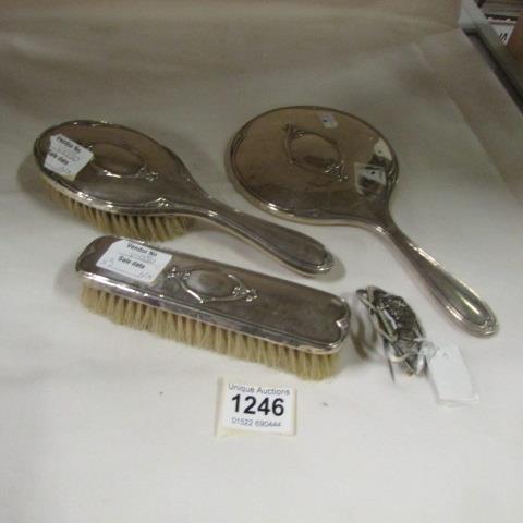 A silver backed hand mirror and 2 matching brushes