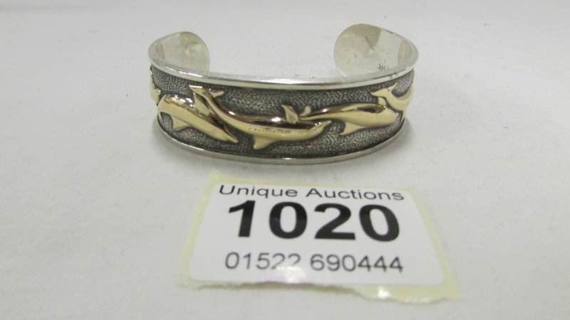A silver and 14ct gold bangle depicting dolphins