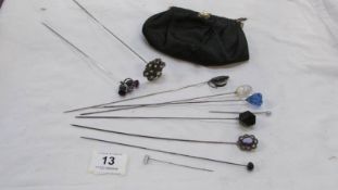 A silver thistle hatpin together with other hatpins and a clutch bag