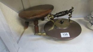A brass and copper kettle and a milking stool
