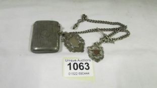 A silver watch chain with 2 silver fobs and a silver vesta