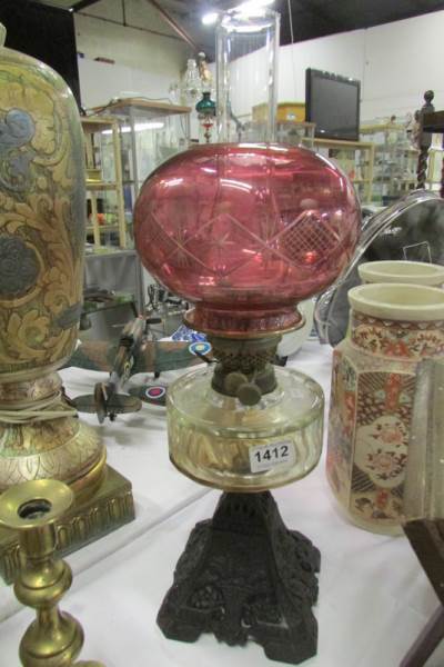 An oil lamp with cast iron base, glass font and later shade