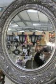 A large oval bevelled glass mirror in silvered frame