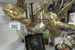 A pair of gilded cherub hanging lamps