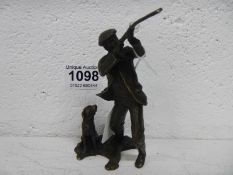 A bronze figure of a man shooting with dog