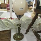 An Art Deco style figurine table lamp with pink glass shade