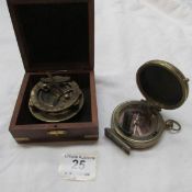 A cased brass compass and one other brass compass