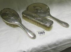 A silver backed hand mirror and 2 matching brushes
