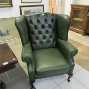 A green leather wing back armchair