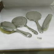 A matching silver backed hand mirror and 2 brushes together with another silver backed hand mirror