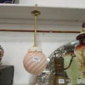 A hanging brass ceiling light with pink Art Deco glass shade