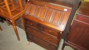 A mid 20th century oak bureau with linenfold top