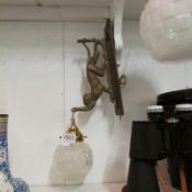 A brass wall light being a monkey hanging from a branch