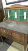 A marble topped washstand with green tiled back