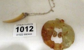 A carved jade toggle and a claw pendant