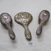 A pair of silver backed brushes and an EPNS mirror depicting Sir Joshua Reynolds 'The Cherub'