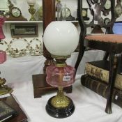 A Victorian oil lamp with cranberry glass font