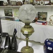 A brass oil lamp with acid etched shade