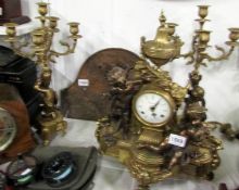 A brass clock garniture surmounted cherubs