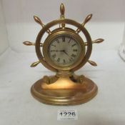 A brass clock in the shape of a ship's wheel